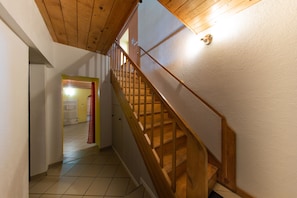 A wooden staircase with a handrail, leading to a room with a tiled floor and a door at the end. - Le Domaine - Prestigious house with private SPA (Osenbach)