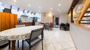 Une cuisine moderne avec un coin repas, des poutres apparentes en bois au plafond et une vue par la fenêtre.