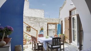 A patio with a table and chairs, a stone wall, and a blue archway. - Lefkara View (Pano Lefkara)