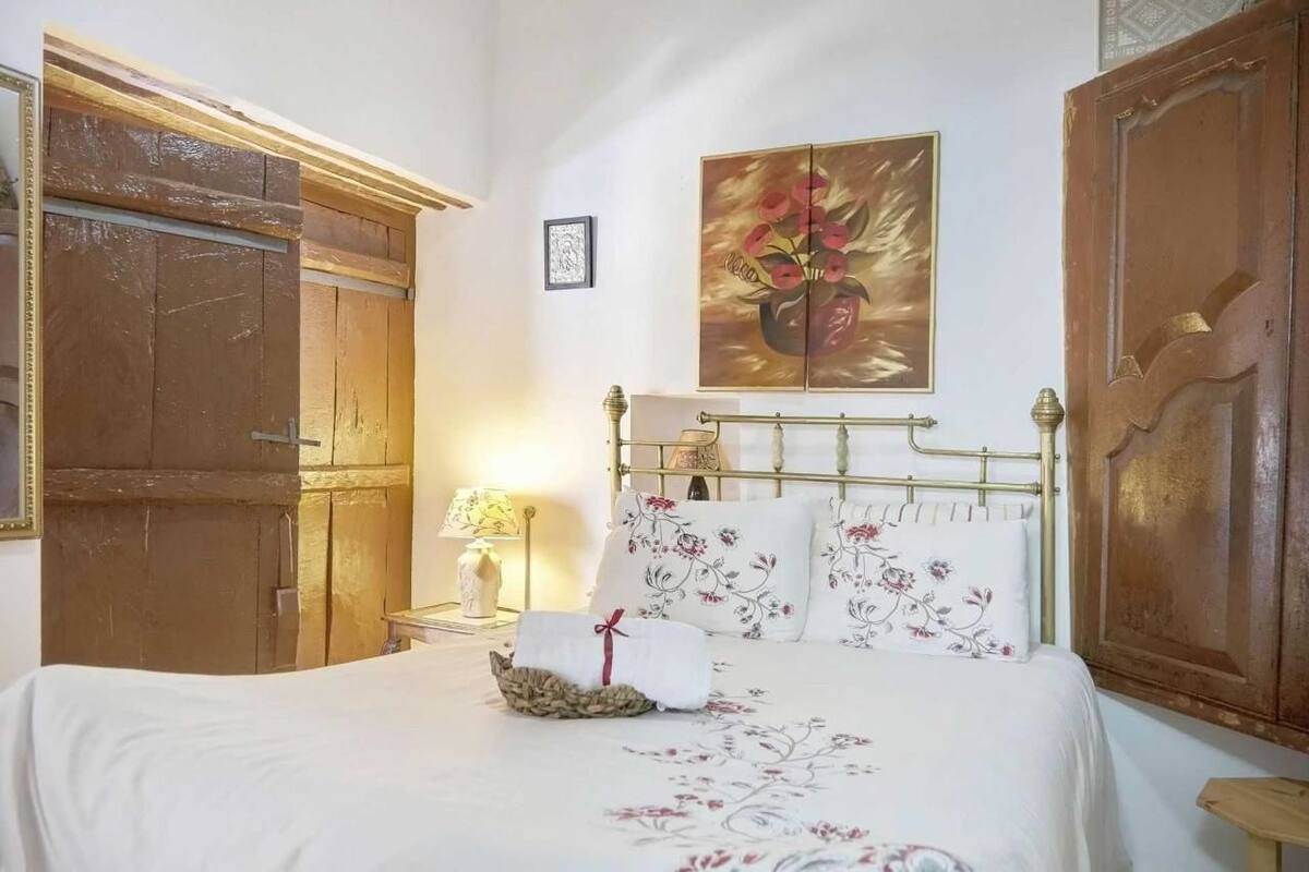 Une chambre à coucher avec un lit, une table de chevet, une lampe, un tableau et des portes en bois.