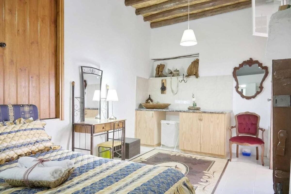 Une chambre à coucher comprenant un lit, un bureau, une chaise, un miroir et une armoire.