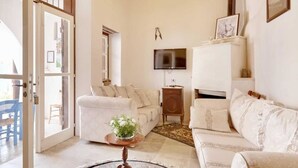 A living room with a sofa, a coffee table with a plant, a TV mounted on the wall, and a wooden side table. - Lefkara View (Pano Lefkara)