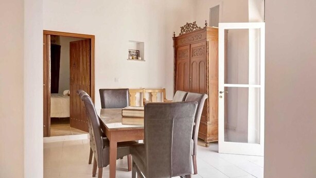 A dining area with a wooden table and chairs, a cabinet, and a door leading to another room. - Lefkara View (Pano Lefkara)