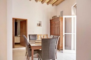 A dining area with a wooden table and chairs, a cabinet, and a door leading to another room. - Lefkara View (Pano Lefkara)