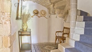 A rustic interior with stone walls, a wooden chair, a table with a vase, and a staircase. - Spacious Mas 18th century,for 10 persons,  private pool, near Uzès (Belvézet)