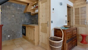 A kitchen with wooden cabinets, a tiled backsplash, and a red stool.