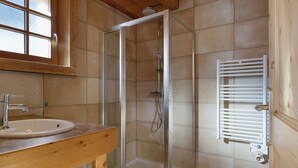 A bathroom with a wooden vanity, a glass shower enclosure, and a white towel rack.