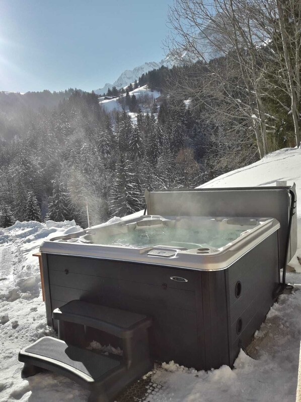 A hot tub in a snowy outdoor setting with a mountainous backdrop.