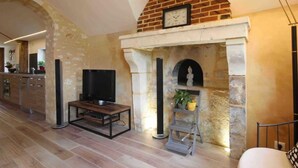 Una sala de estar con chimenea de piedra, televisión y una escalera que sube a un nivel superior.