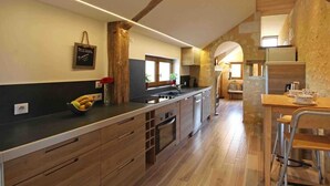 Una cocina moderna con armarios de madera, una isla central y un comedor con sillas de metal.