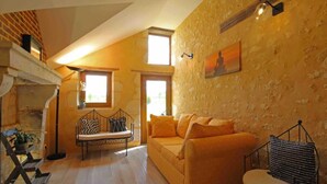 Una sala de estar acogedora con suelo de madera, un sofá, un banco y una chimenea.