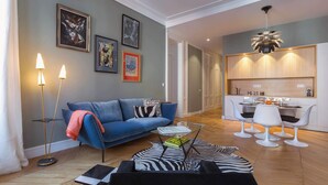 A modern living room with a blue sofa, a glass coffee table, and a zebra-patterned rug. - Confort - Furnished apartment - Downtown Lyon (Lyon)