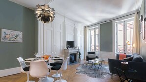 A spacious living room with a fireplace, modern furniture, and large windows. - Confort - Furnished apartment - Downtown Lyon (Lyon)