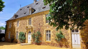 Un bâtiment en pierre doté d’un toit en pente, de nombreuses fenêtres et d’une entrée centrale avec une porte.