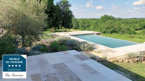 Une piscine entourée d’une végétation luxuriante et dotée d’une terrasse en pierre.