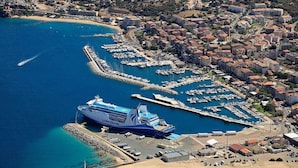A cruise ship docked at a marina with a coastal town in the background. - SANA - CASA SULTANA (PROPRIANO)
