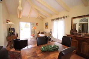 A dining area with a wooden table, black chairs, and a decorative centerpiece. There is a sofa and a lamp in the background. - SANA - CASA SULTANA (PROPRIANO)
