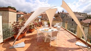 A rooftop terrace with a round table and chairs, surrounded by potted plants and a white umbrella. - SANA - CASA SULTANA (PROPRIANO)