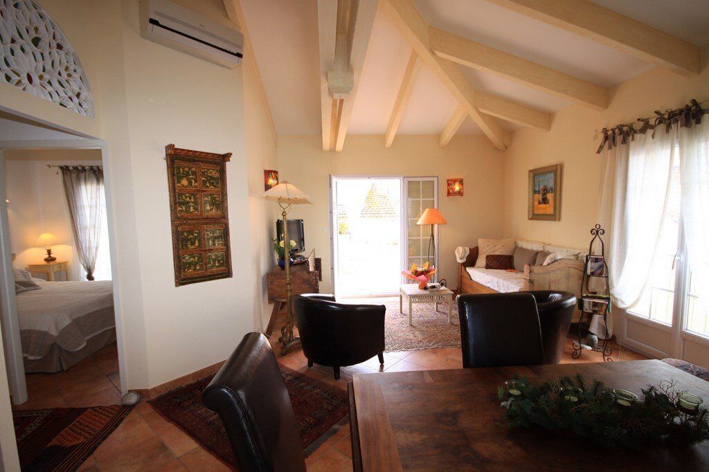 A cozy living room with a wooden ceiling, a dining table, and a sofa.