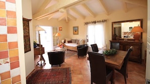 A spacious living room with a high ceiling and exposed beams, a dining area with a wooden table and chairs, and a kitchen area with a large mirror and a lamp. - SANA - CASA SULTANA (PROPRIANO)