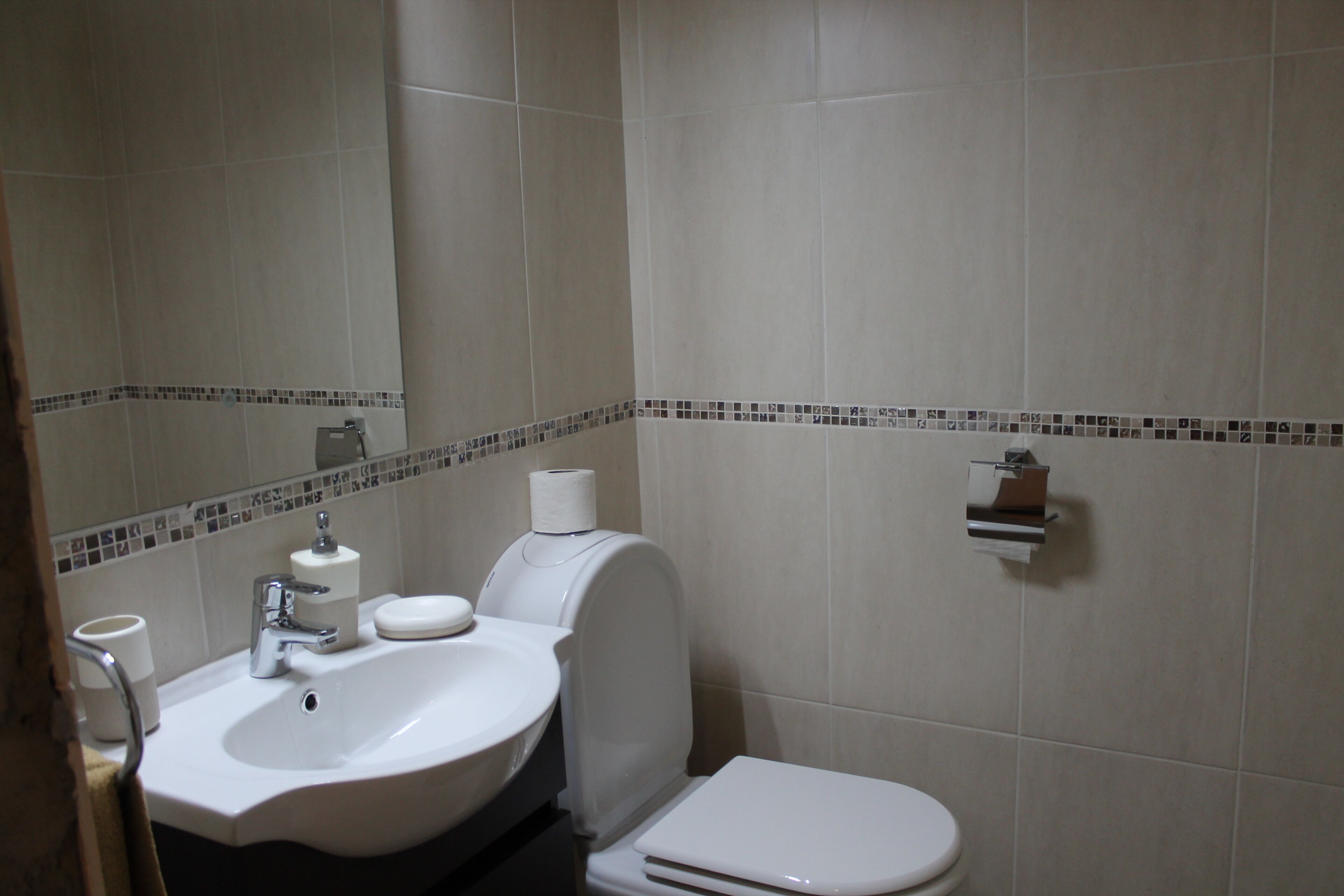 A bathroom with a sink, toilet, and a mirror.