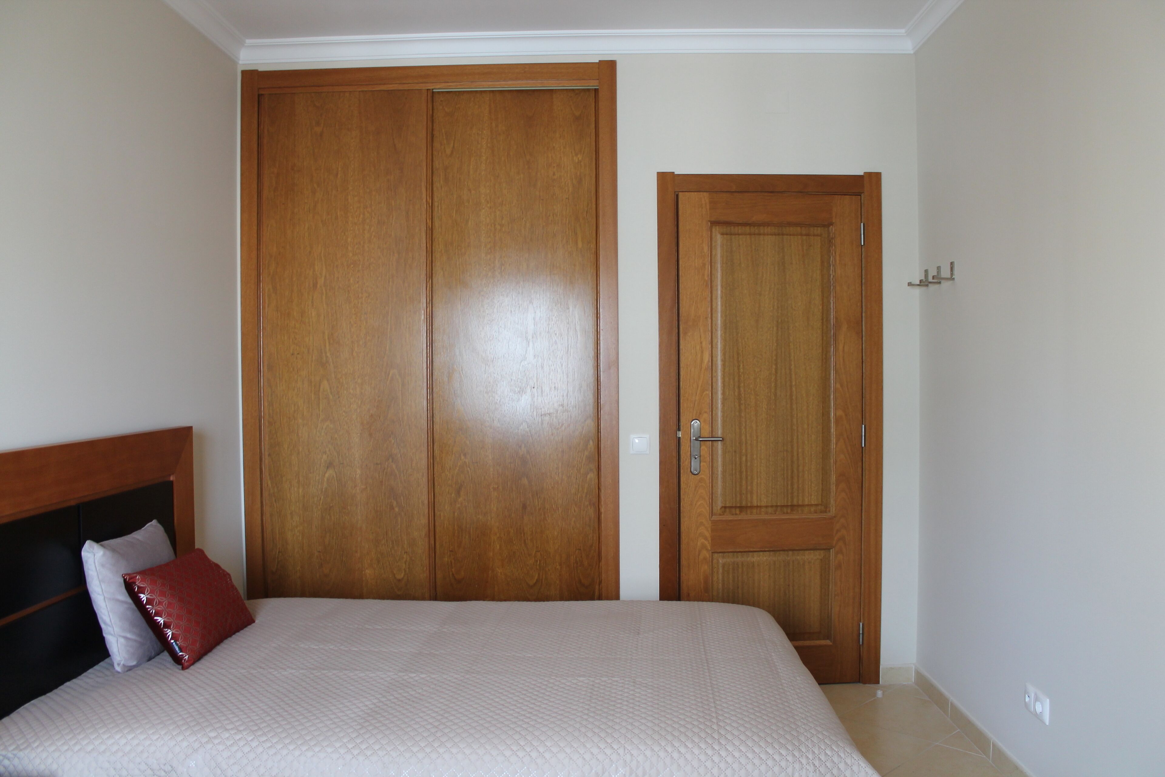 Un dormitorio con cama, armario de madera y puerta.