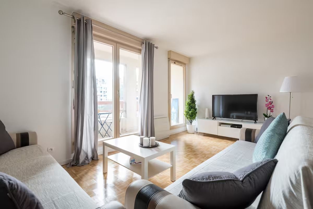 A modern living room with a sofa, a coffee table, and a flat-screen TV.