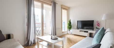 A modern living room with a sofa, a coffee table, and a flat-screen TV.