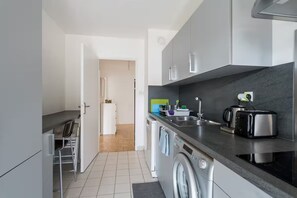 Cozinha compacta com máquina de lavar, torradeira e pia.