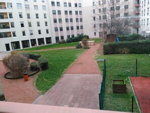 A courtyard with a paved walkway, green lawns, and a small playground area.