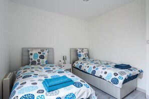 Une chambre à coucher avec deux lits, chacun doté d’une couette à motifs, d’une table de chevet et d’une lampe.