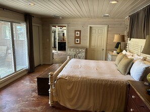 A bedroom with a large bed, a dresser, a nightstand, and a window.