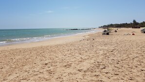 A beach with clear skies, calm waters, and a few boats on the sand.