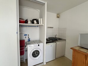 A compact kitchen with a washing machine, a sink, and a small countertop.
