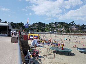 A beach with inflatable play areas, a stage, and a sign for 'Ecole de Natation'. - Studio de Standing &Proximité Plages 800M & 300M Commerces et port (Perros-Guirec)