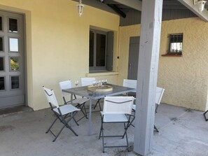 Terrassa exterior amb taula i cadires, una finestra i una porta.
