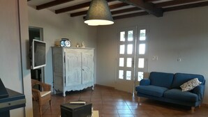 Un saló amb un sofà blau, un armari blanc, una televisió i una taula amb una caixa i un got.