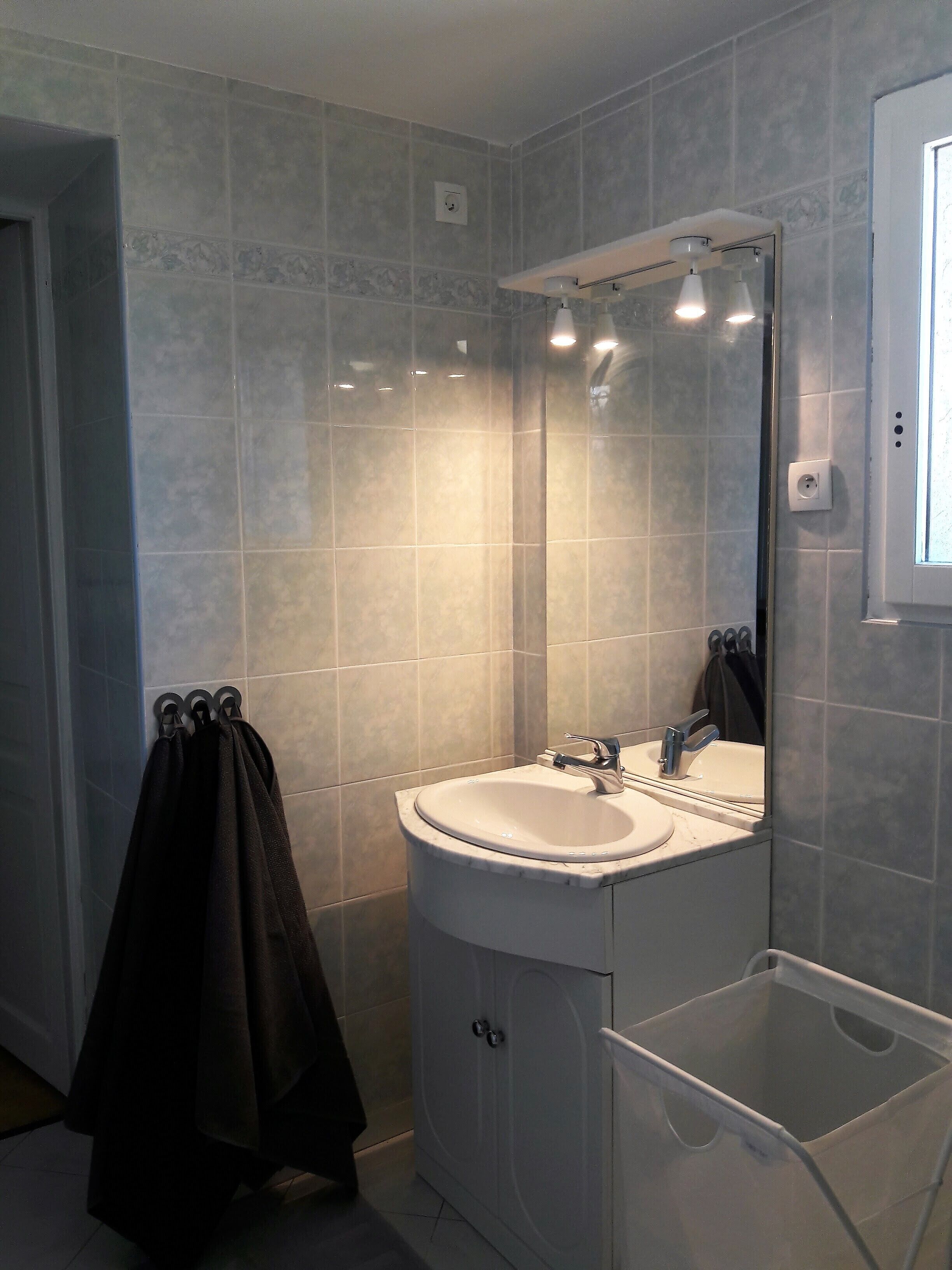 A bathroom with a white sink, a mirror, and a shower area.