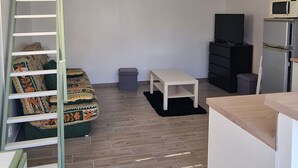 A compact living space with a loft bed, a small white table, a microwave, and a refrigerator. - SUNNY HOME / STUDIO ALL EQUIPPED (Cuges-Les-Pins)
