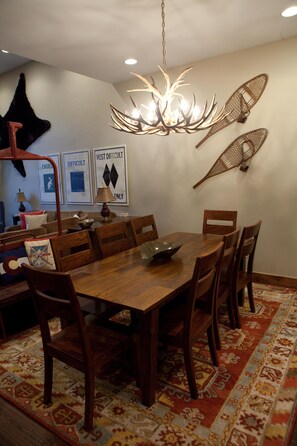 A dining area with a wooden table and chairs, a chandelier, and wall art. - Luxury condo, walking distance to Lionshead Gondola 4B  & 4B premier partner (Vail)