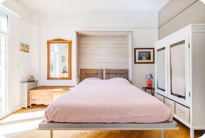 Une chambre à coucher comprenant un lit, une commode, un miroir et une armoire.