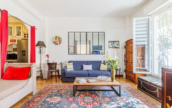 Un salon avec un canapé bleu, une table basse et un tapis à motifs.