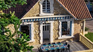 Un bâtiment en pierre avec un toit recouvert de tuiles, un balcon doté d’une balustrade et une table mise pour le repas.