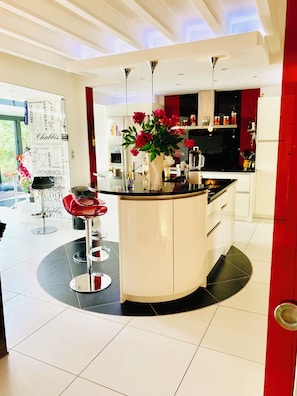 Une cuisine moderne avec un îlot central, des tabourets de bar et un mur d’accent rouge.