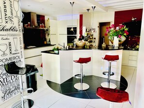 Une cuisine moderne dotée d’un îlot central, de tabourets de bar et d’un mur décoratif orné de motifs textuels.