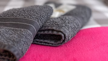 Ein graues, zusammengerolltes Handtuch auf einer rosafarbenen Fläche.