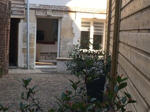 A courtyard with a gravel path, a potted plant, and a brick wall. - The Lieutenance, 45m2, terrace, WIFI, Honfleur center (Honfleur)