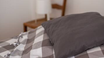 Un lit avec une couvre-lit à carreaux et un oreiller gris.
