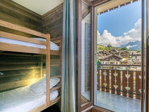 Ein Zimmer mit Etagenbetten und einem großen Fenster mit Blick auf eine Stadt mit Gebäuden und Bergen.