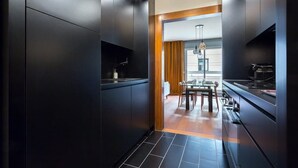 A modern kitchen with dark cabinetry, a dining area with a wooden table and chairs, and a view into the living space. - Stella - Furnished apartment - Downtown Lyon (Lyon)